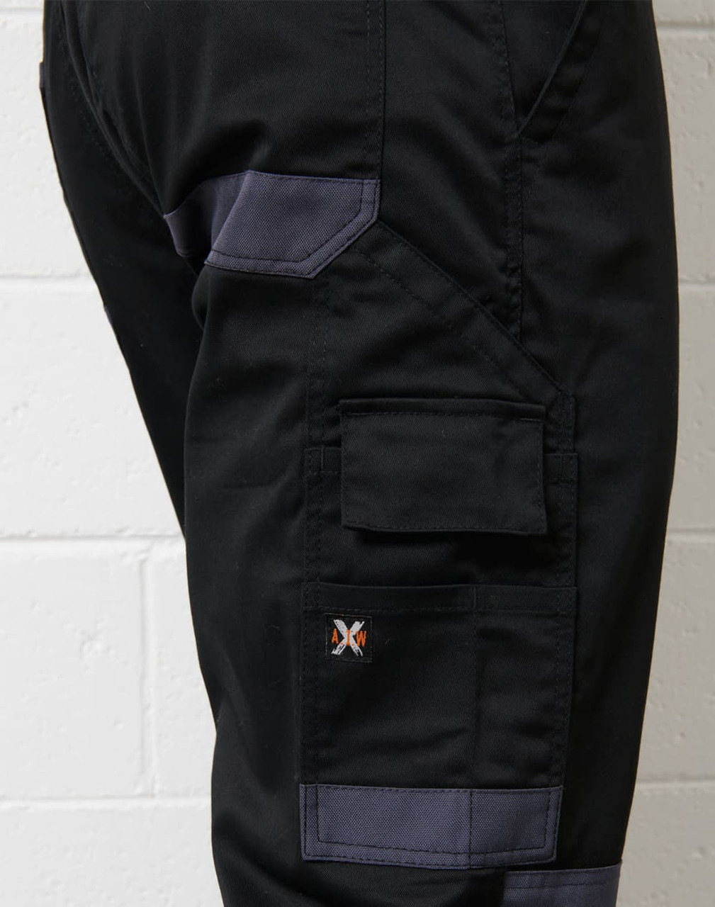 A close-up of black cargo pants featuring grey accents and a logo on the side.