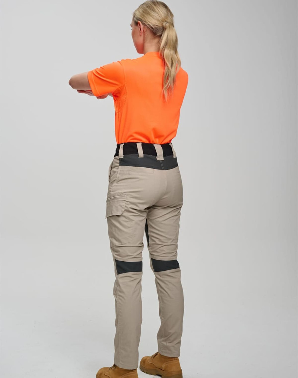 Light beige work pants featuring a stretch design and a black waistband, paired with an orange shirt. The image has a logo.