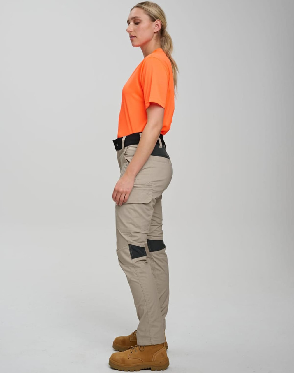 Work pants in light khaki with black accents, paired with an orange shirt. The model stands in profile.