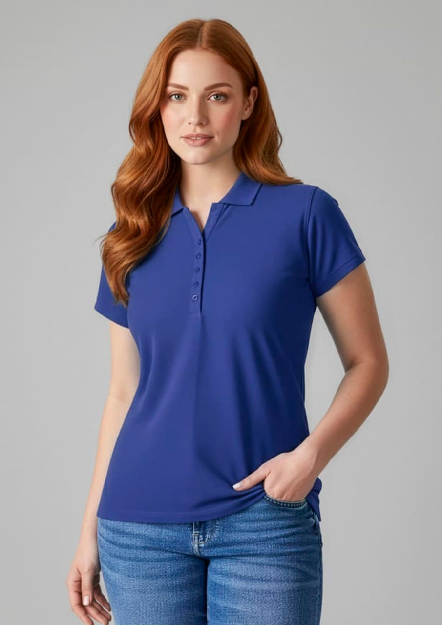 A blue ladies polo shirt with a collar and short sleeves, featuring a logo. Model wearing it with jeans.