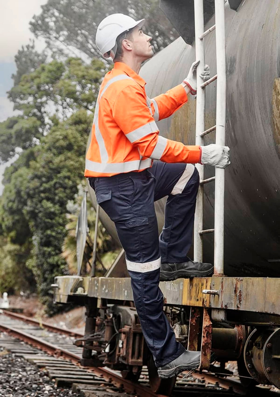 A man wearing an orange flame lightweight ripstop taped shirt climbs a ladder on a train, surrounded by greenery.