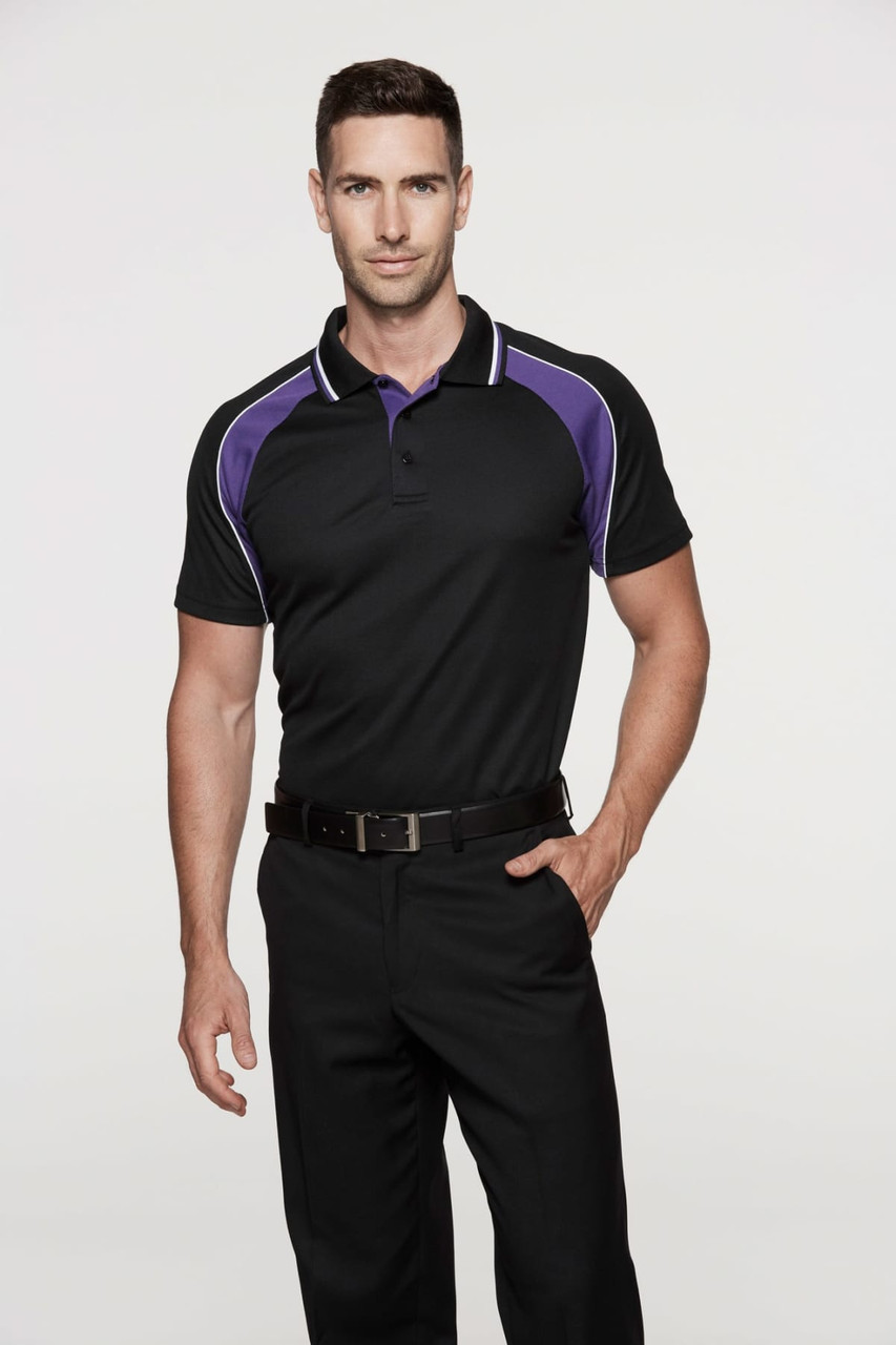 A model wearing a black polo shirt with purple detailing, paired with black trousers. The shirt features a logo.