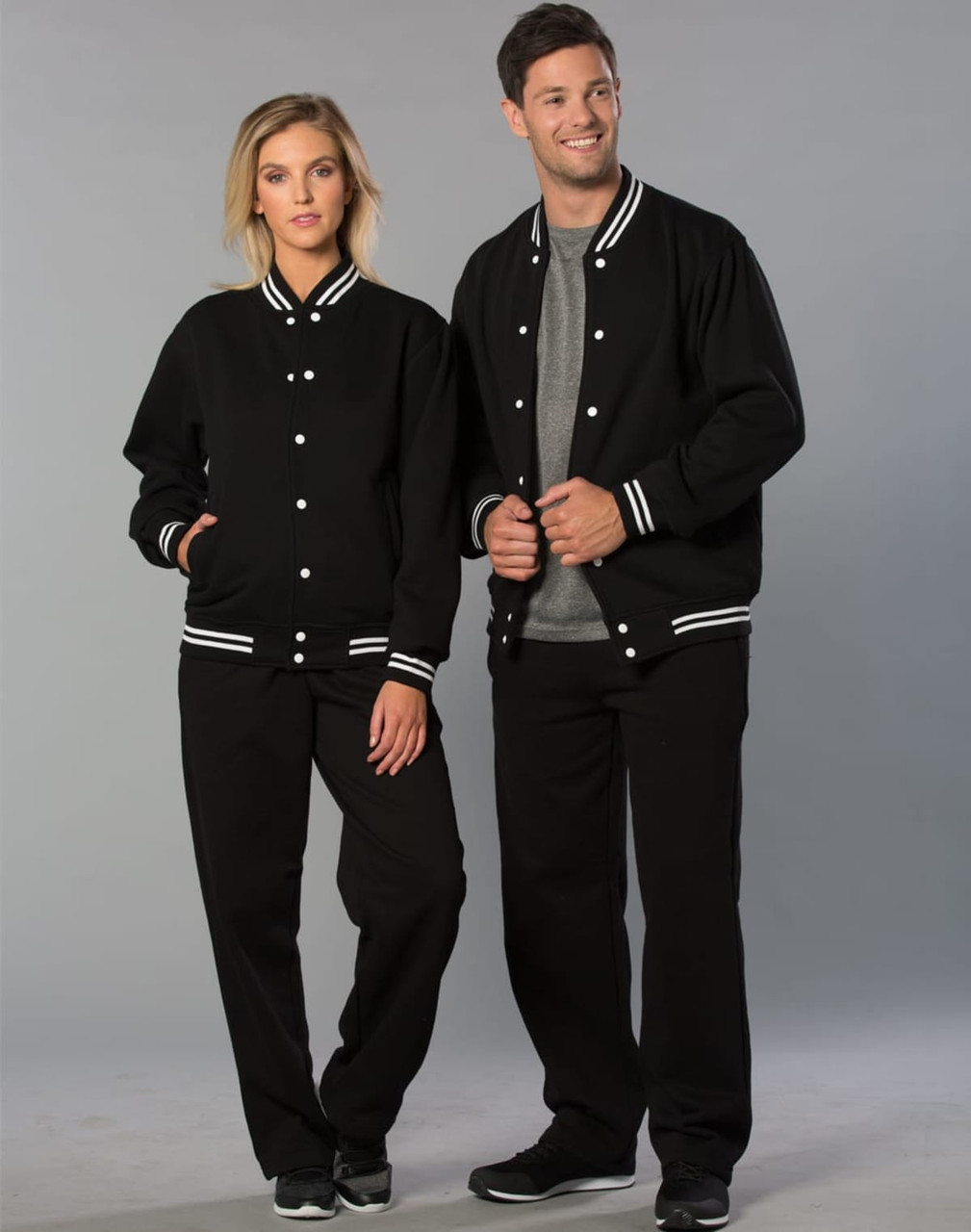 Black track pants for adults featured with matching black jackets, both with white stripes. Accessories visible include logo branding.