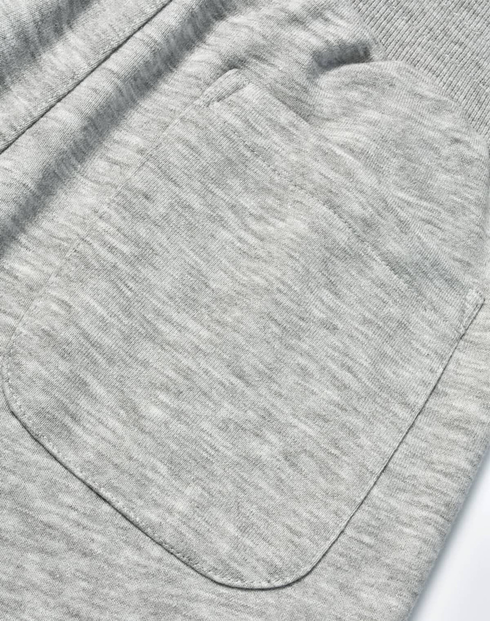A close-up of grey poly/cotton terry fabric featuring a large pocket on sweat pants.
