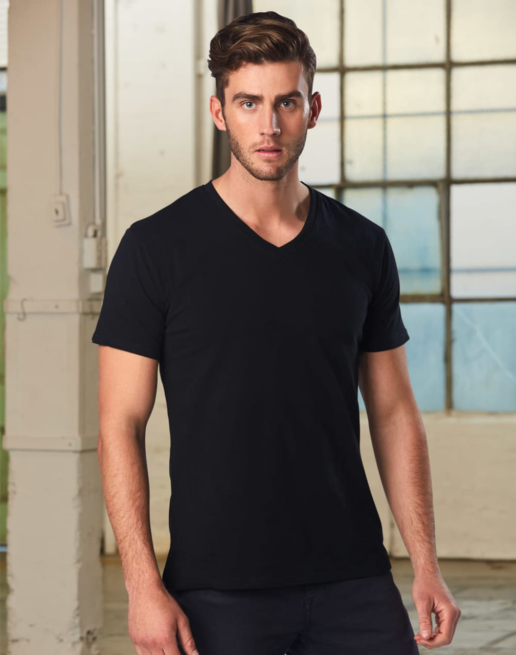 A men's black V-neck short sleeve tee, displayed on a model with a neutral background and natural lighting.