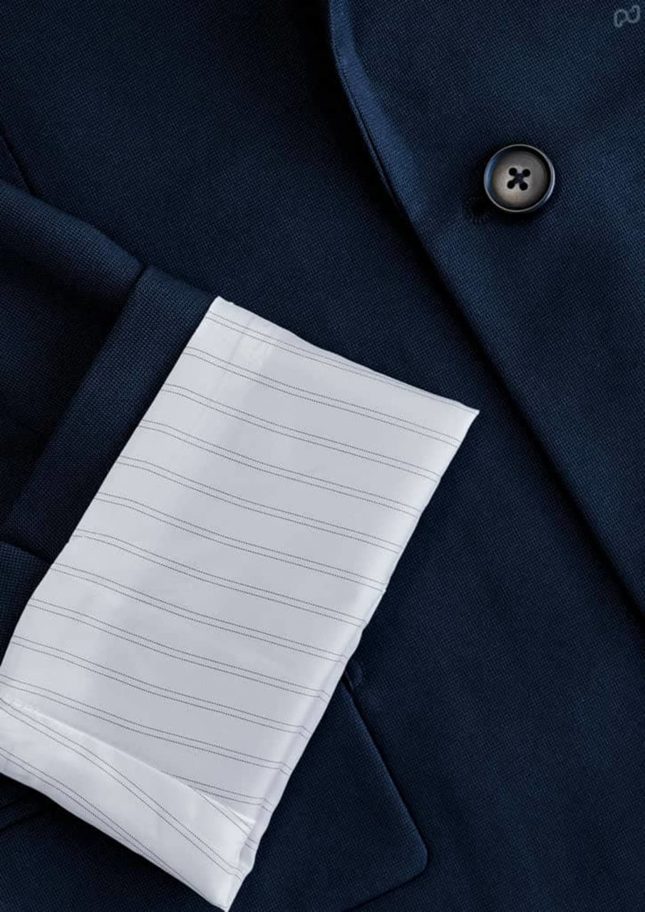 A navy jacket featuring a white striped cuff and a button detail, with a branding logo present.