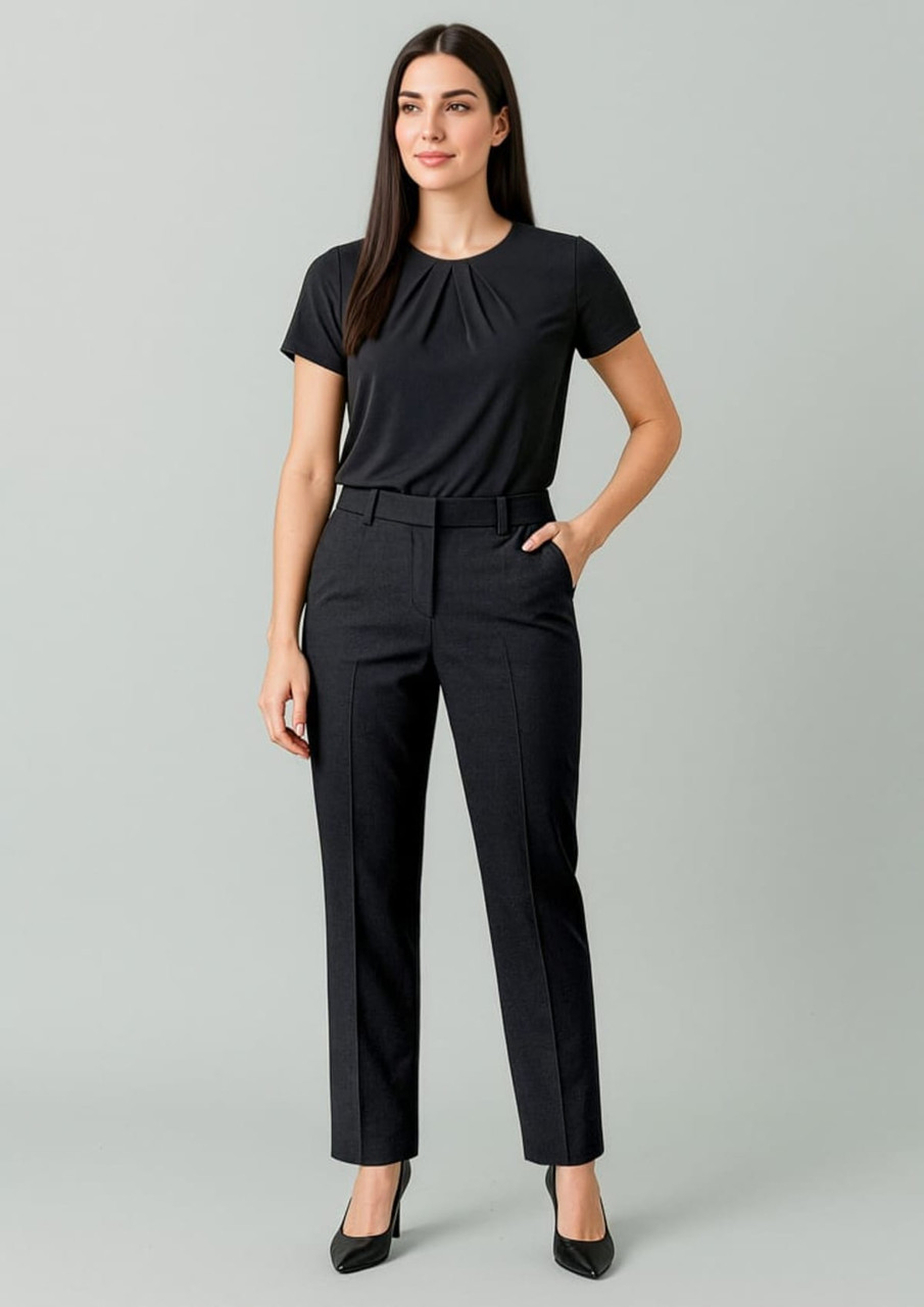 A woman in a black top and tapered black slacks with an adjustable waist, standing against a neutral background.