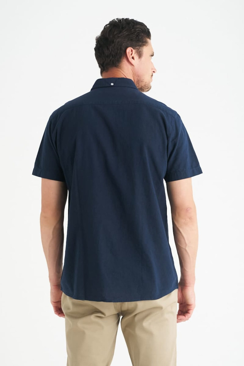 A navy short sleeve button-up shirt with a collar, featuring a back view of a model.