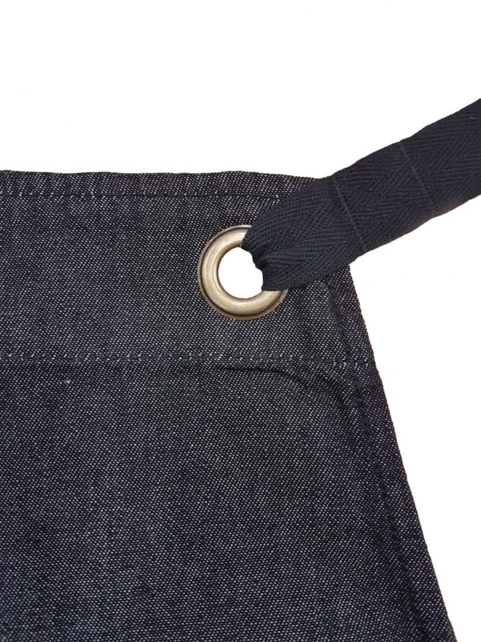 A dark denim bib apron featuring a metal grommet for adjustable ties. It includes a branding logo.