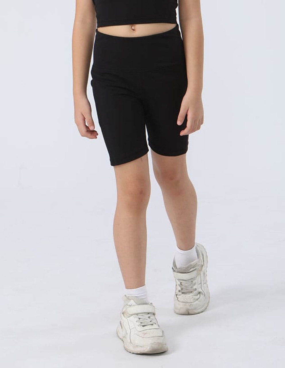 Black girl's legging shorts with a fitted design, paired with white sneakers, set against a light background.
