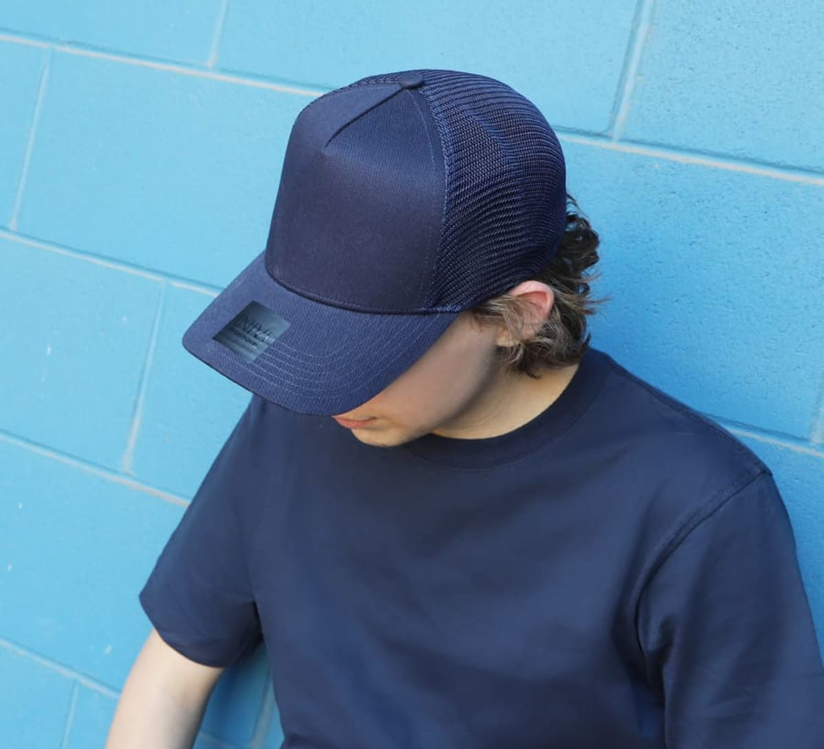 A navy blue cap with a mesh back, resting on the head of a person wearing a matching navy shirt.