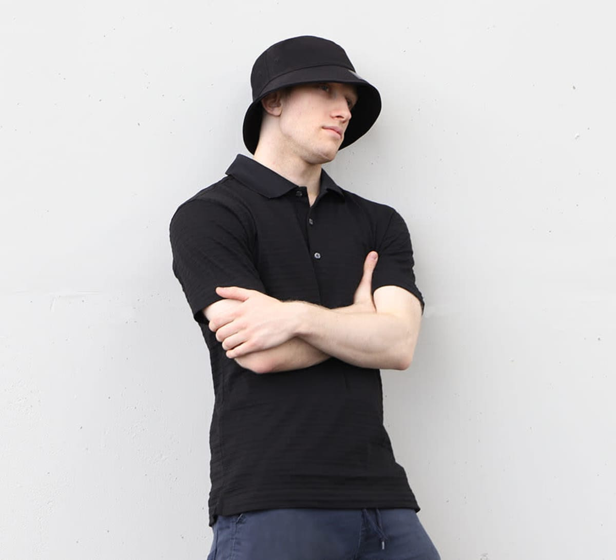 A black cotton/spandex bucket hat displayed on a model wearing a matching black polo shirt. The hat features a logo.