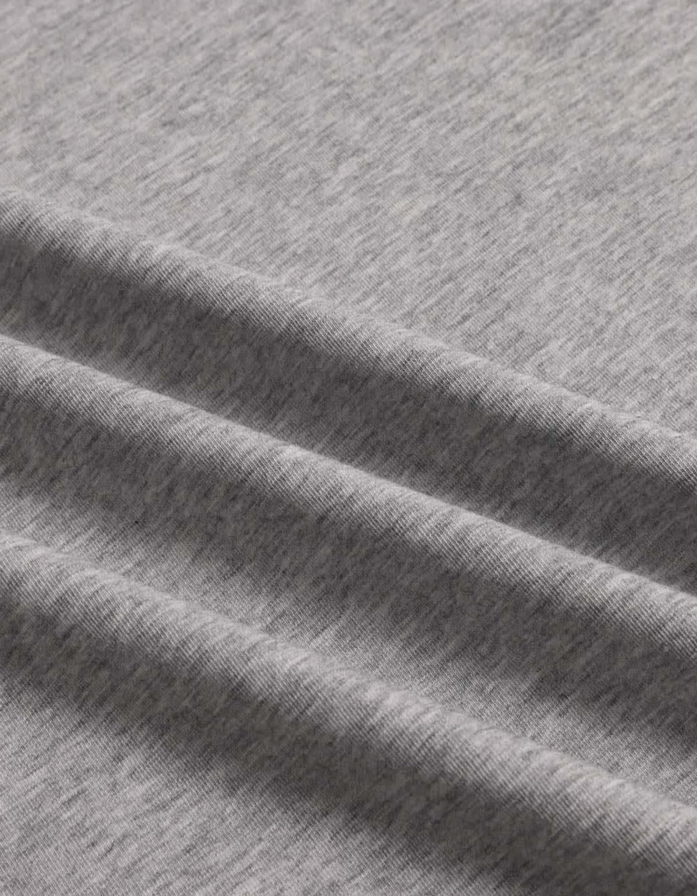 A close-up of a grey premium cotton T-shirt fabric, featuring a soft, textured finish and gentle folds.