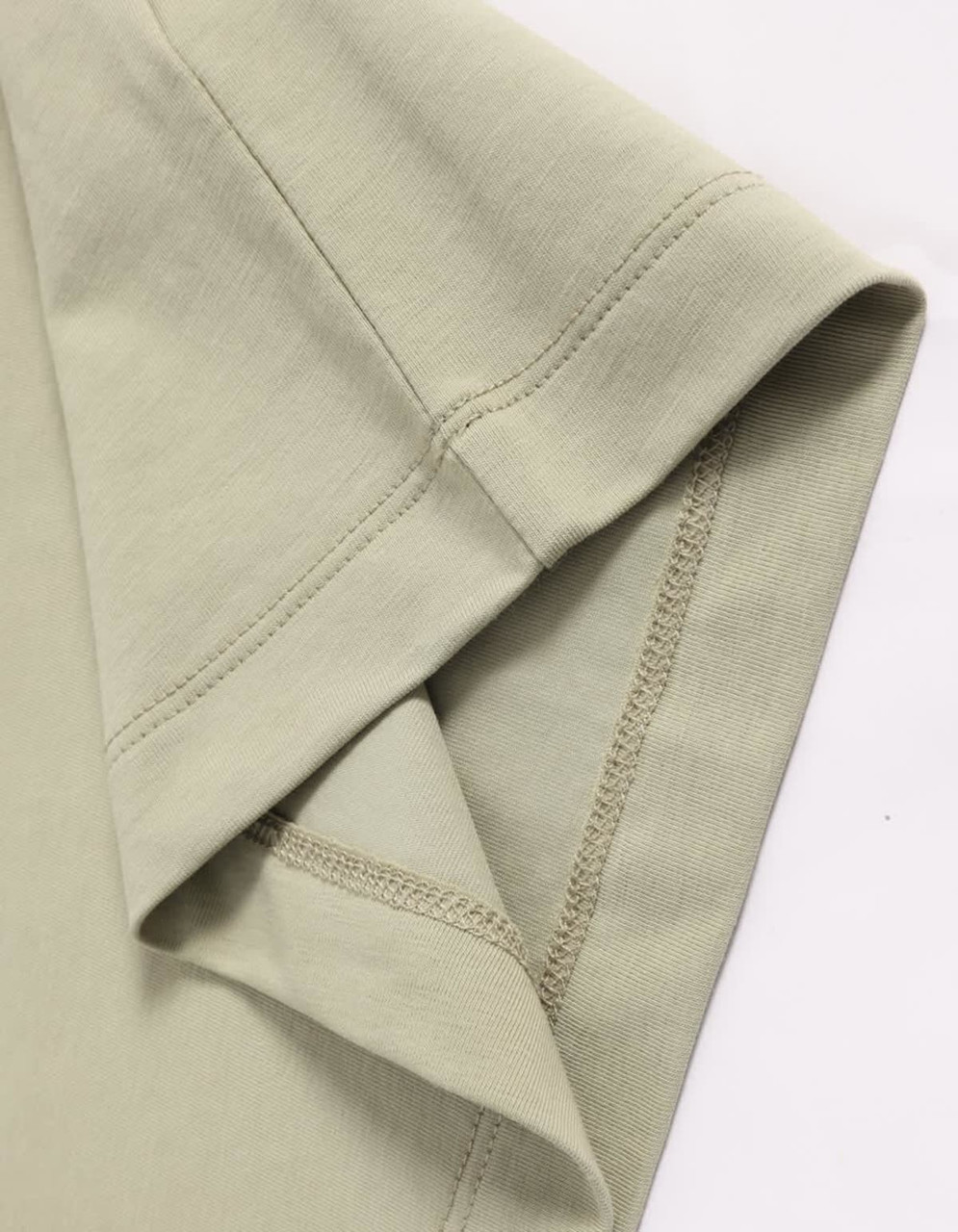 A close-up of a light green premium cotton short-sleeve tee shirt with a stitched hem and sleeve detail.