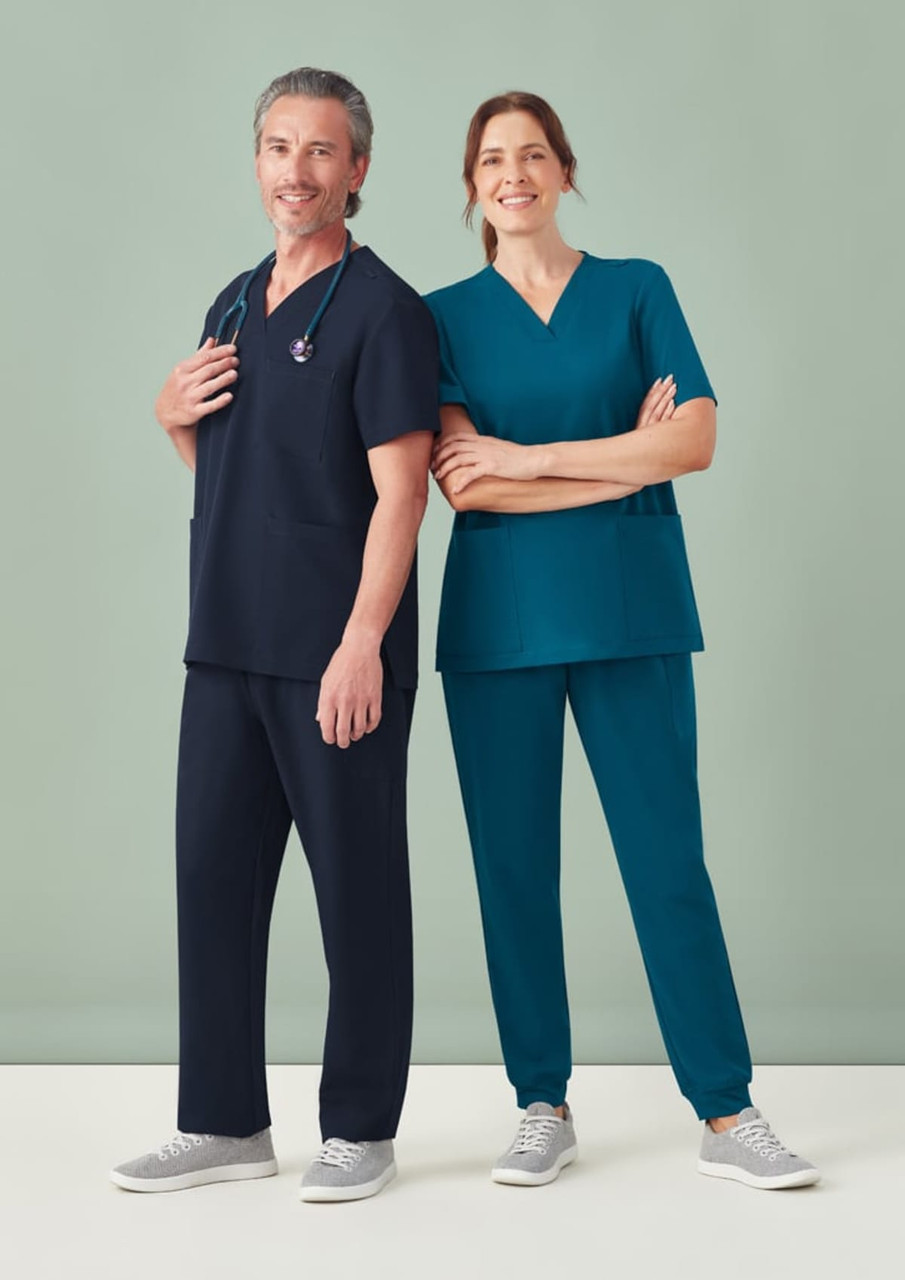 A pair of healthcare professionals wearing navy and teal scrub tops and jogger scrub pants, paired with grey shoes.