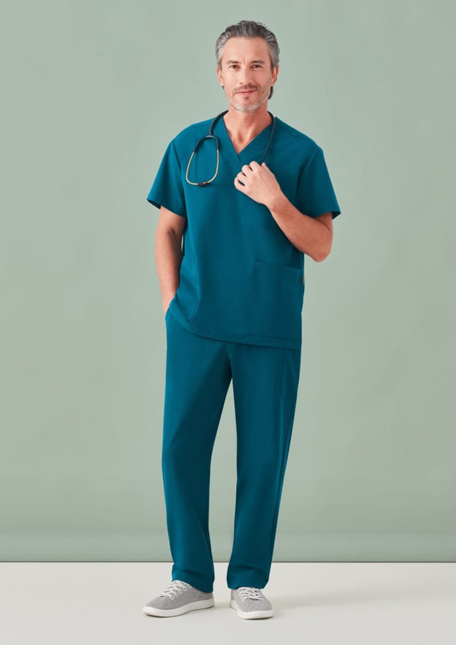 A man in teal unisex scrub pants and a matching top, wearing a stethoscope around his neck.
