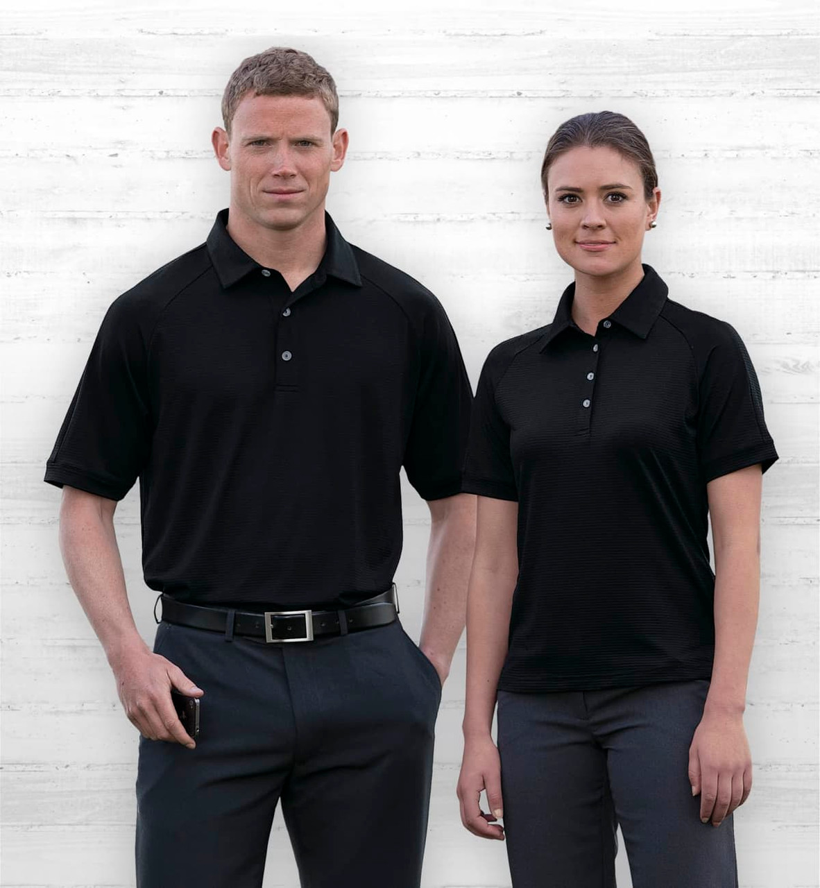 A men's and women's black polo shirt with a logo, displayed on models against a neutral background.