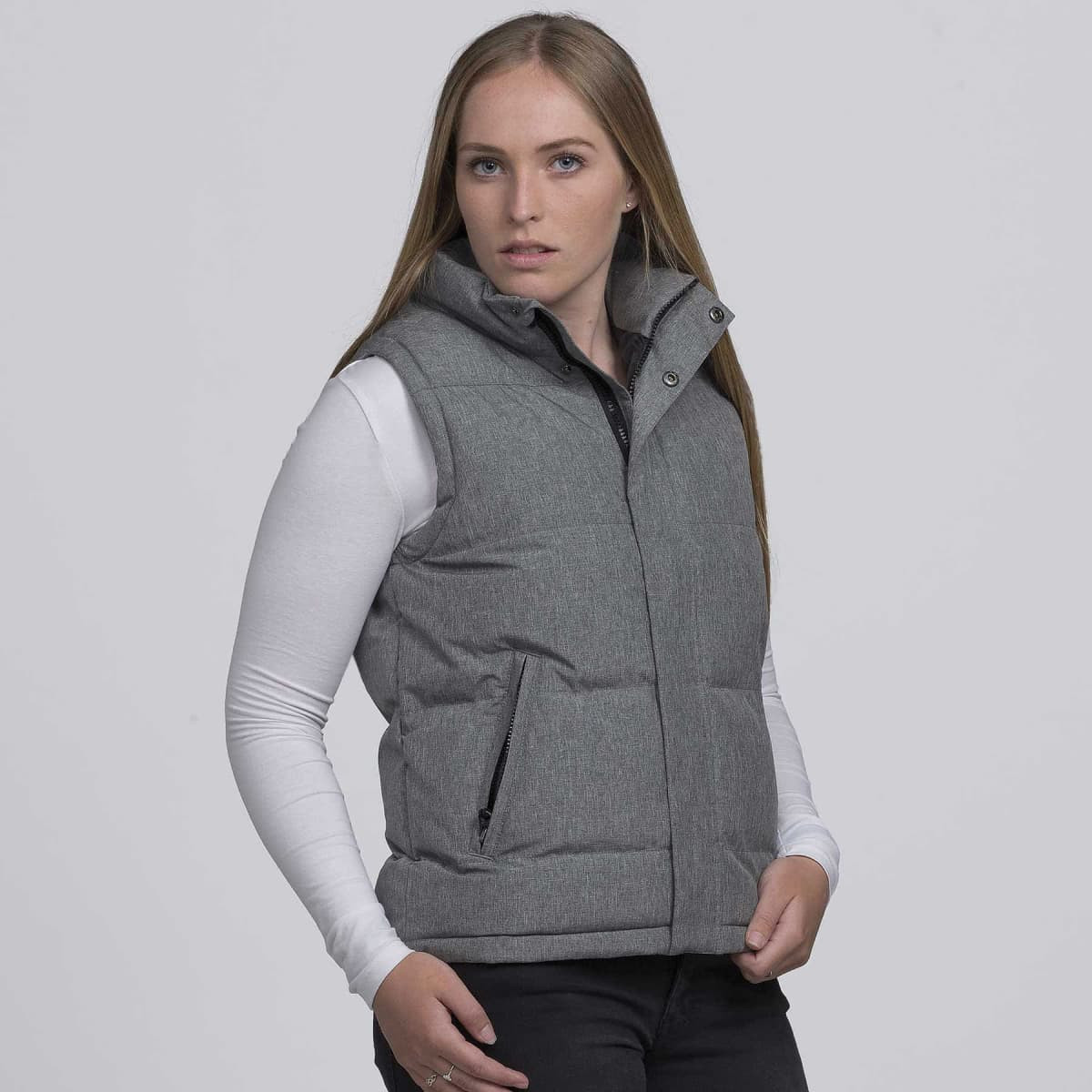 A grey puffa vest with a high collar and side zippers, featuring a model wearing a long-sleeve top underneath.