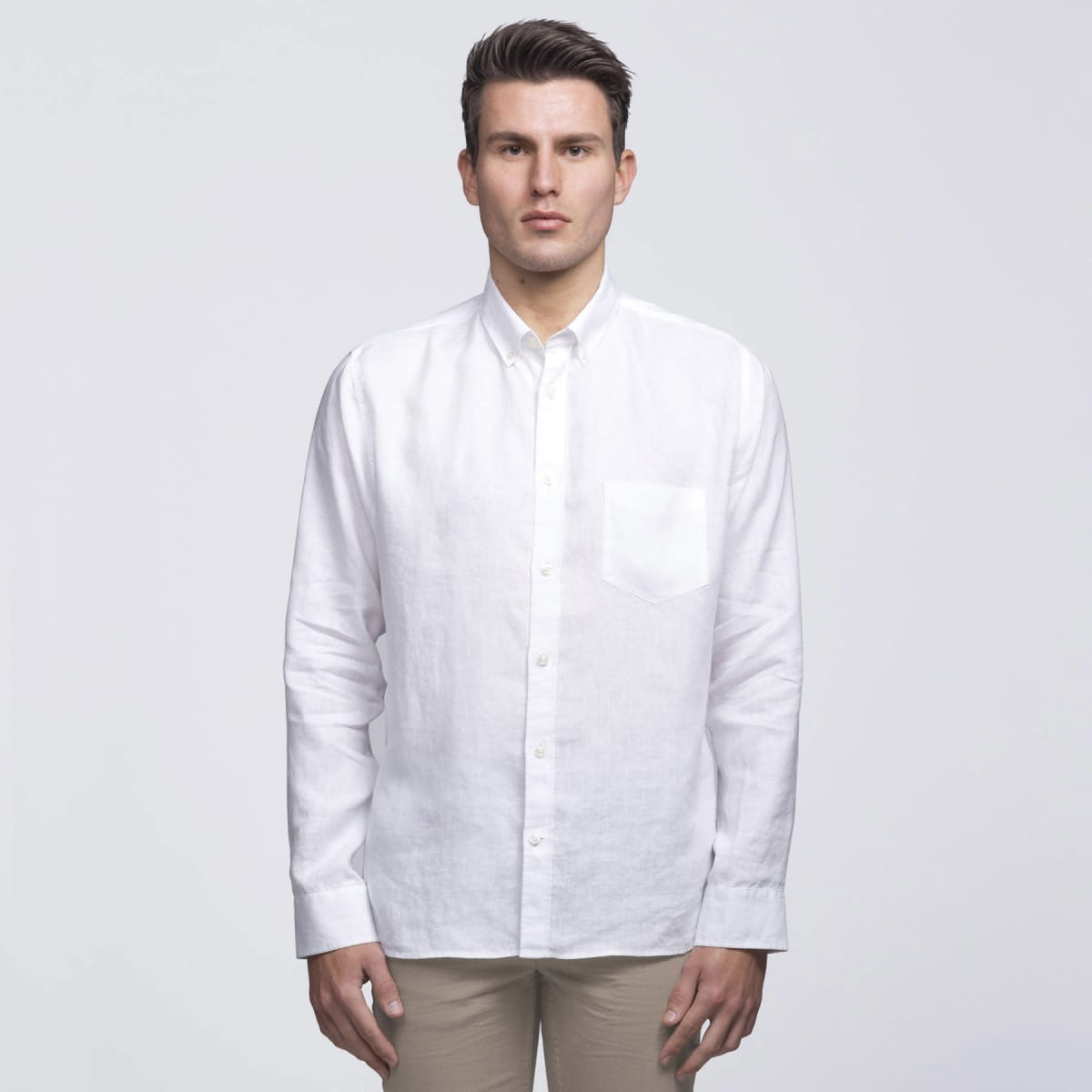 A white linen button-up shirt featuring a chest pocket and a collar, worn by a model against a plain background.