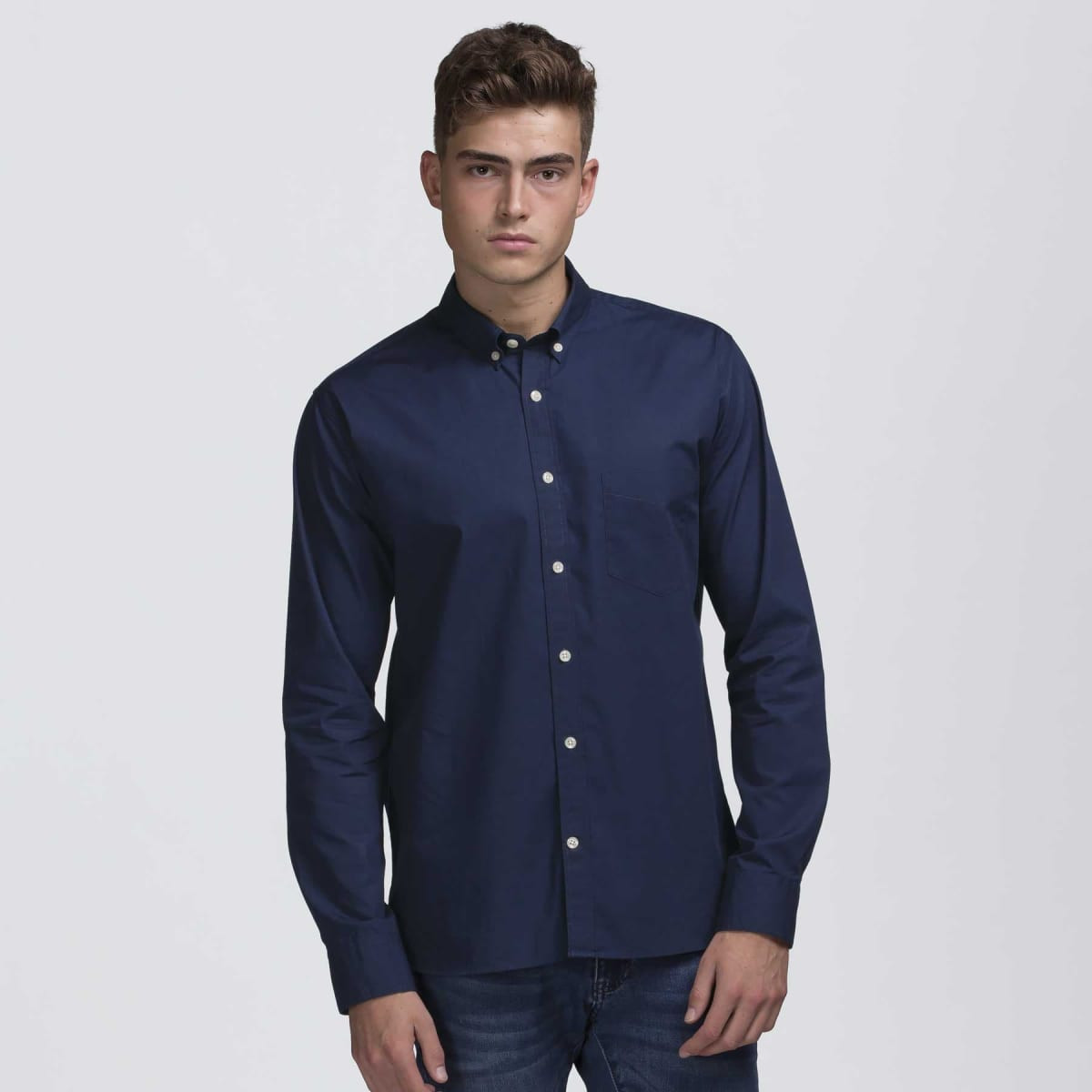 A navy blue button-up shirt with a collar and a chest pocket, modelled by a man. Features branded labels.