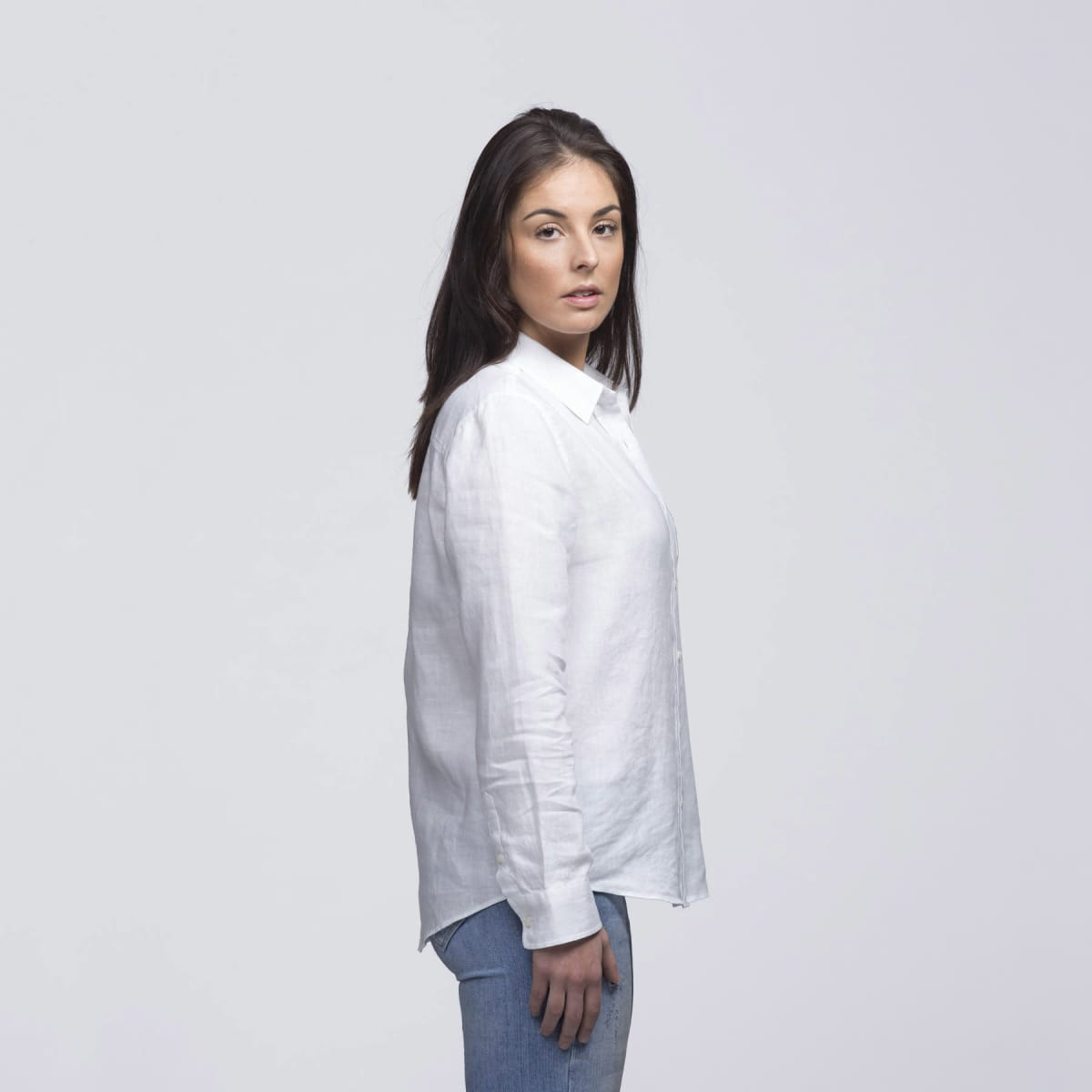 A white linen button-up shirt displayed on a model, featuring a relaxed fit and long sleeves.