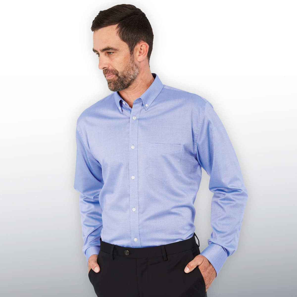 A light blue button-up shirt featuring a pocket and a collar, worn by a man with his hands in his pockets.