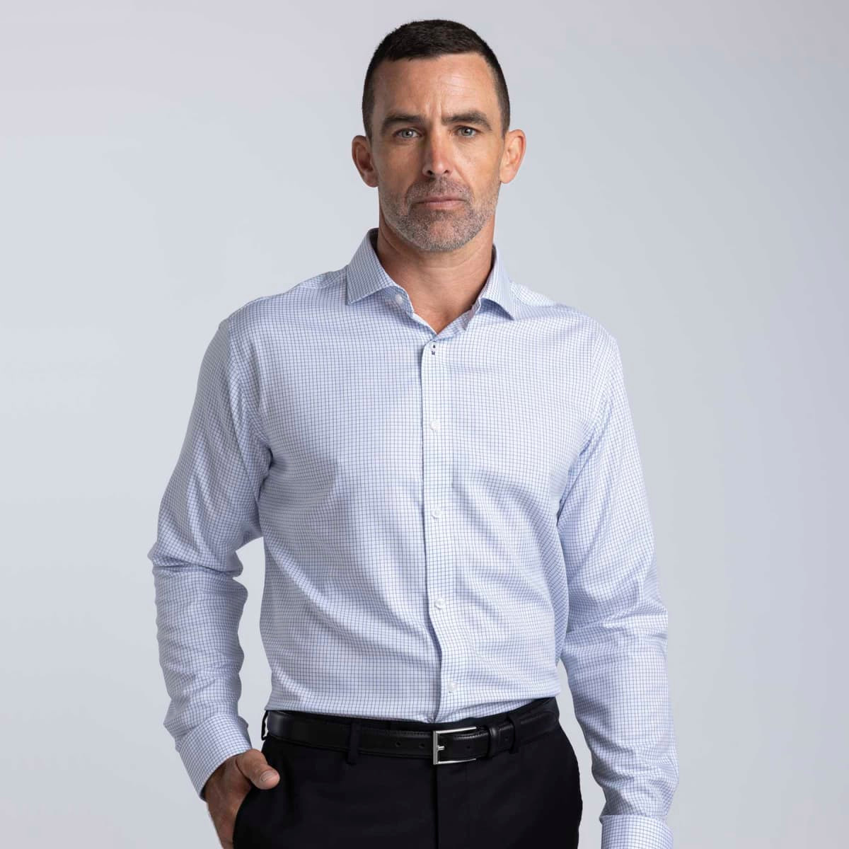 A men's button-up shirt in a blue and white check pattern with a collar and long sleeves. Features a logo.