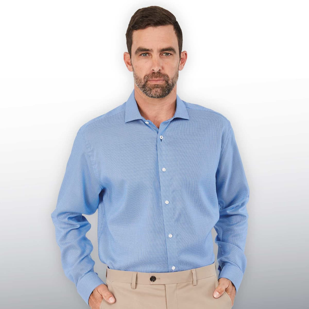 A men's button-up shirt in light blue with long sleeves and a collar, featuring a logo.
