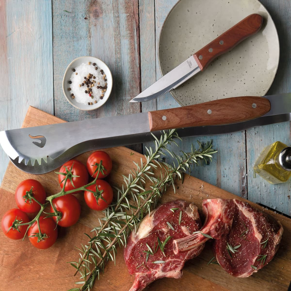 A pair of stainless steel tongs with wooden handles, surrounded by fresh tomatoes, herbs, and a knife on a wooden board.