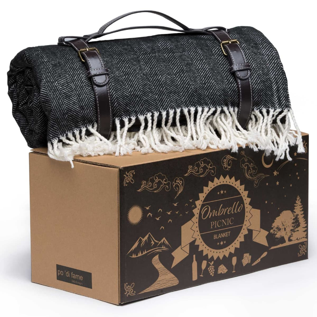 A rolled black and white herringbone picnic blanket with leather straps sits atop a decorative box.