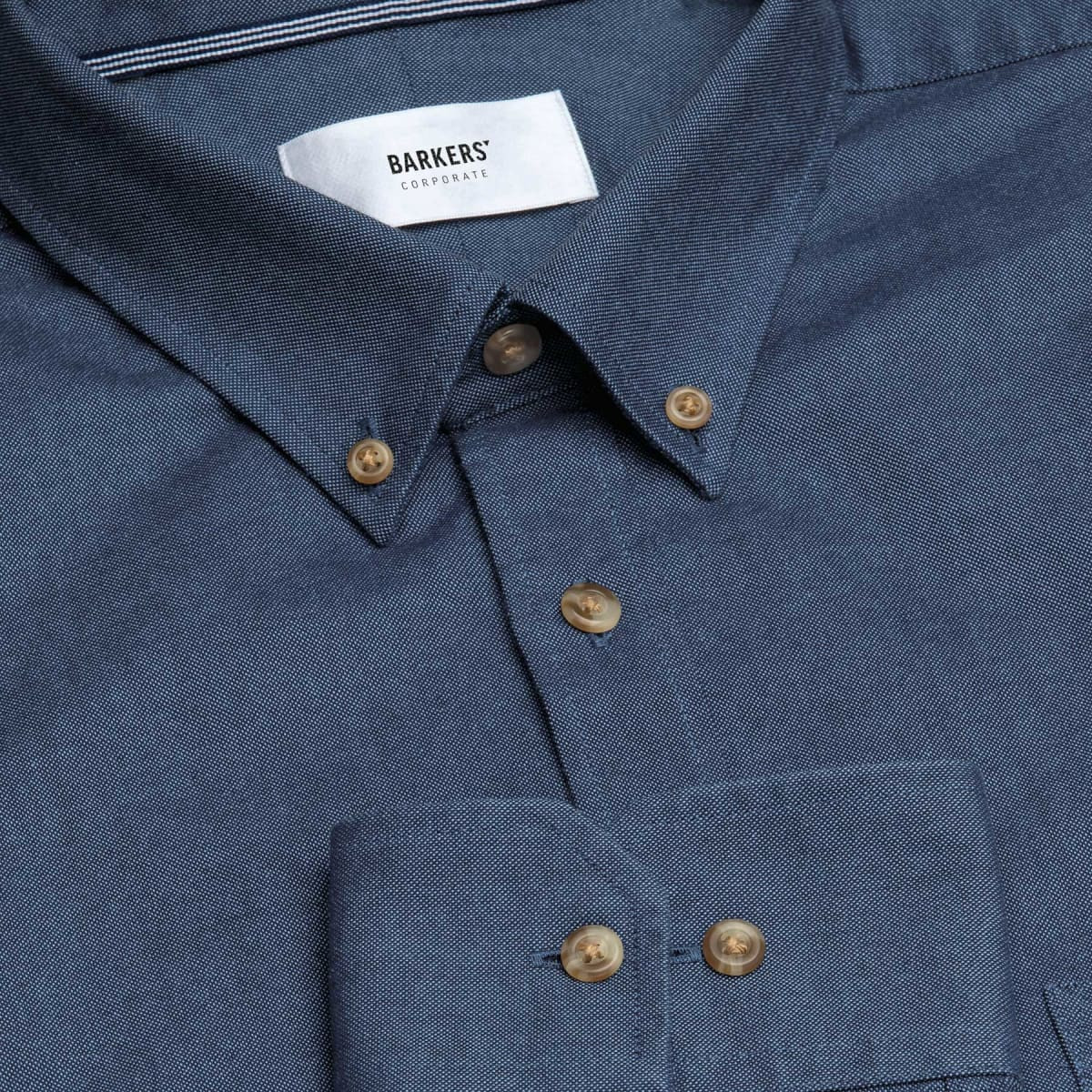A blue button-up shirt with a chest pocket and brown buttons, featuring a collar and a brand logo.