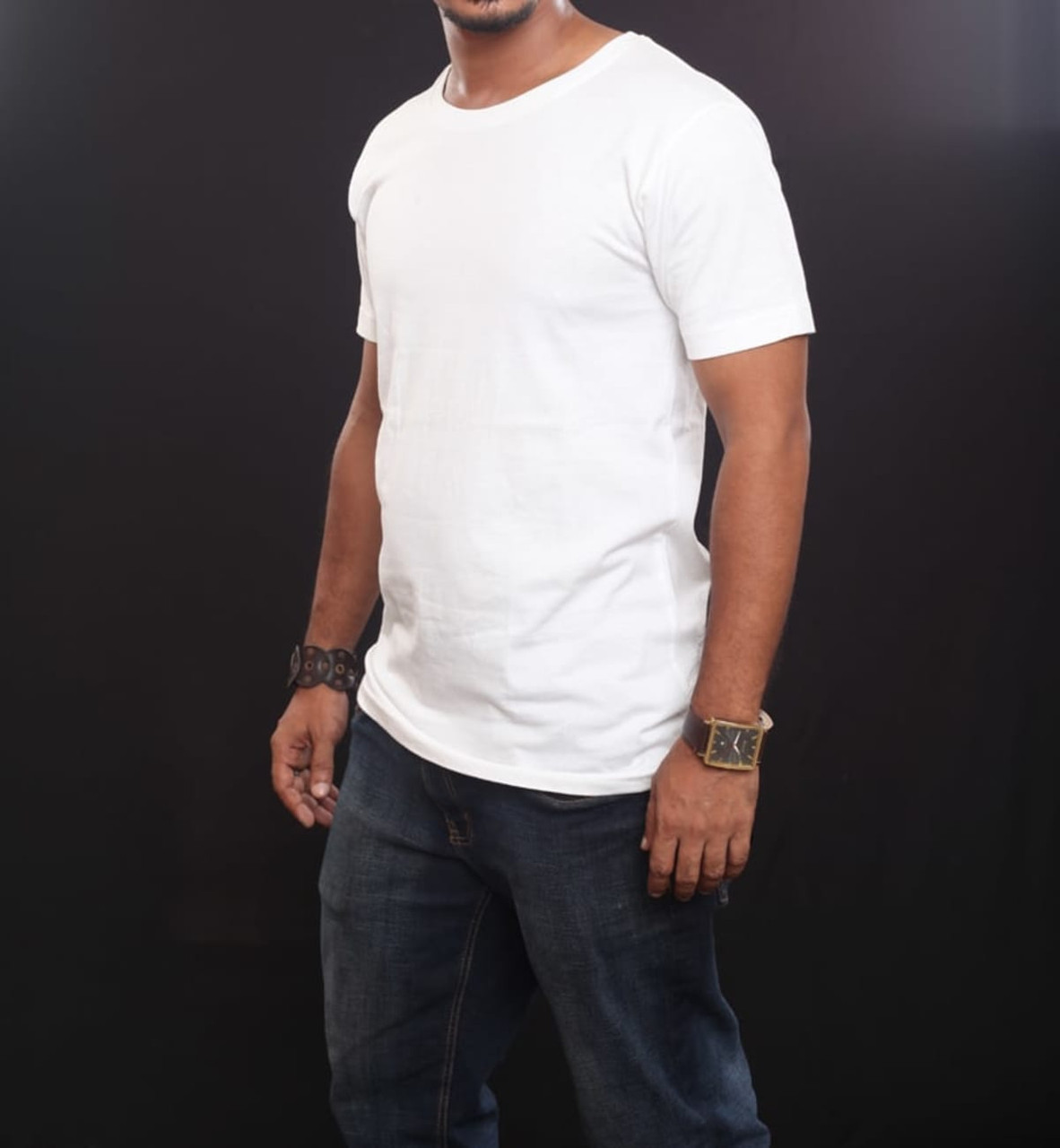 A white t-shirt displayed on a person wearing jeans, featuring a simple design and a logo on the chest area.