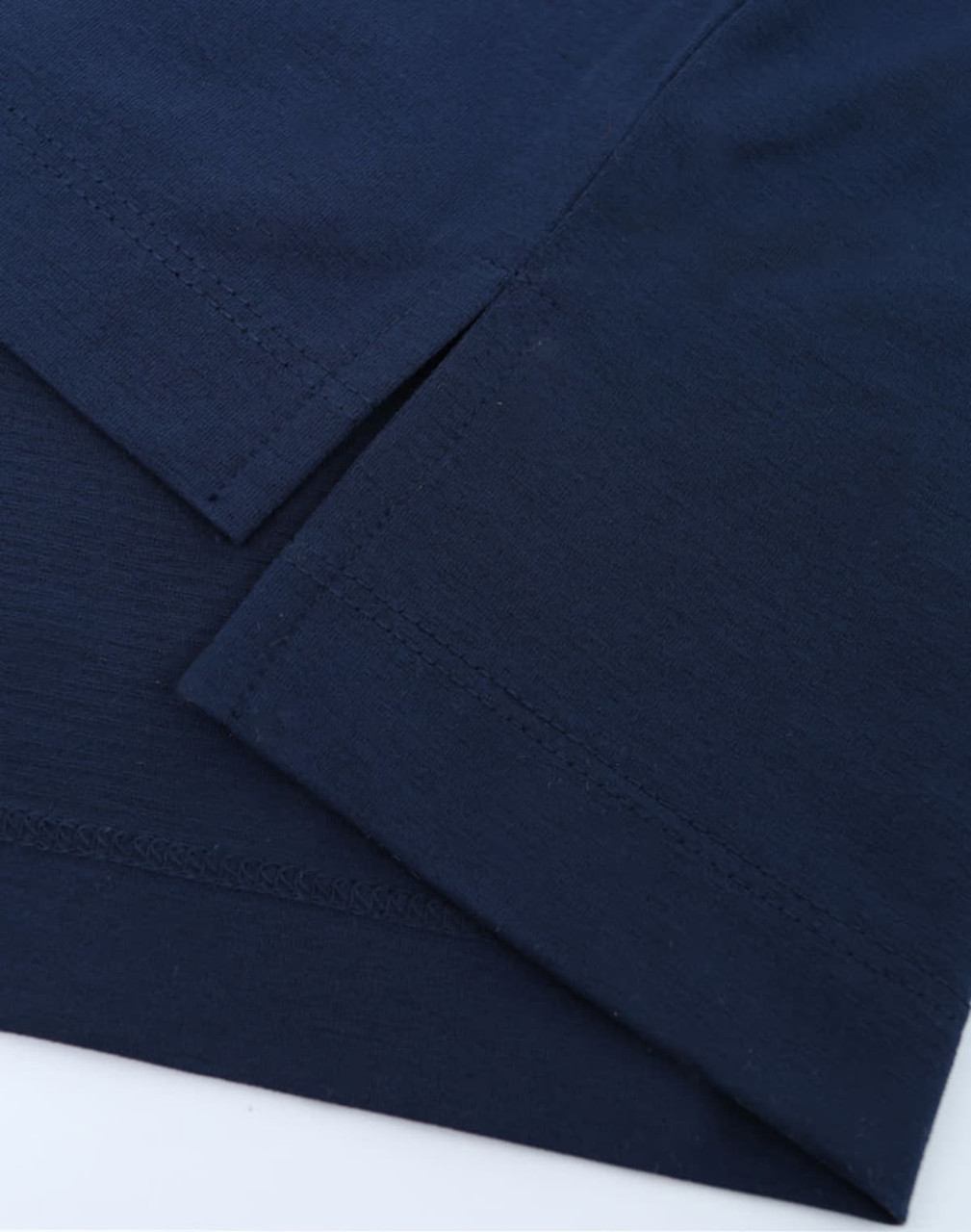 A close-up of a navy blue polo shirt displaying its fabric and hem details. The shirt has a logo.