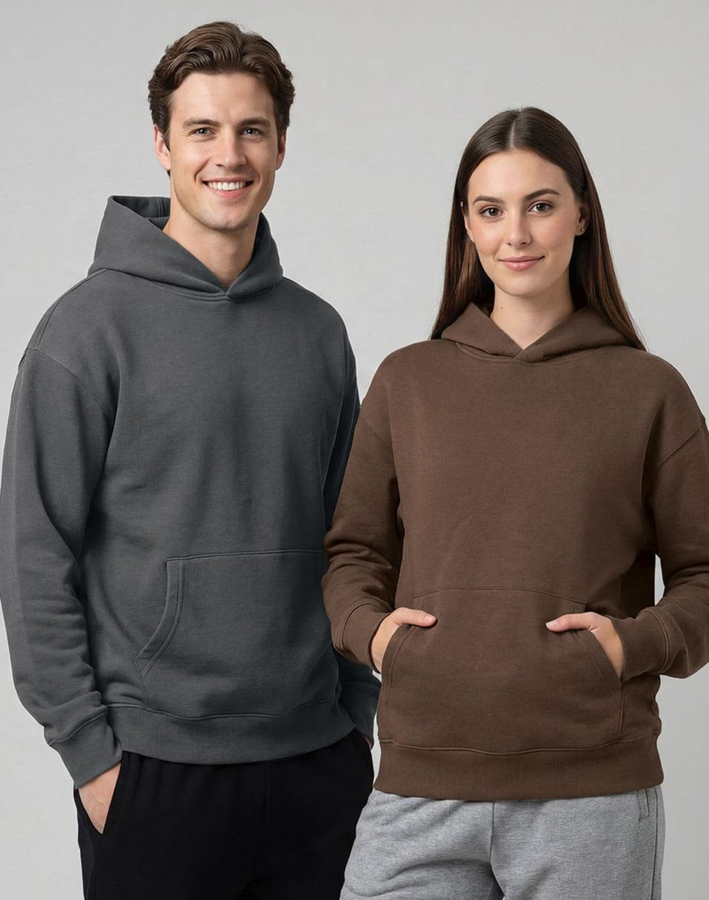 A grey unisex oversized hoodie and a brown unisex oversized hoodie, featuring a front pocket and a hood.