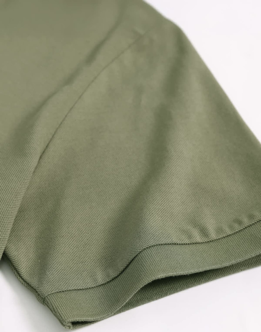 A close-up of a khaki green men's ultrafine cotton pique polo, highlighting the sleeve detail. It features a logo.