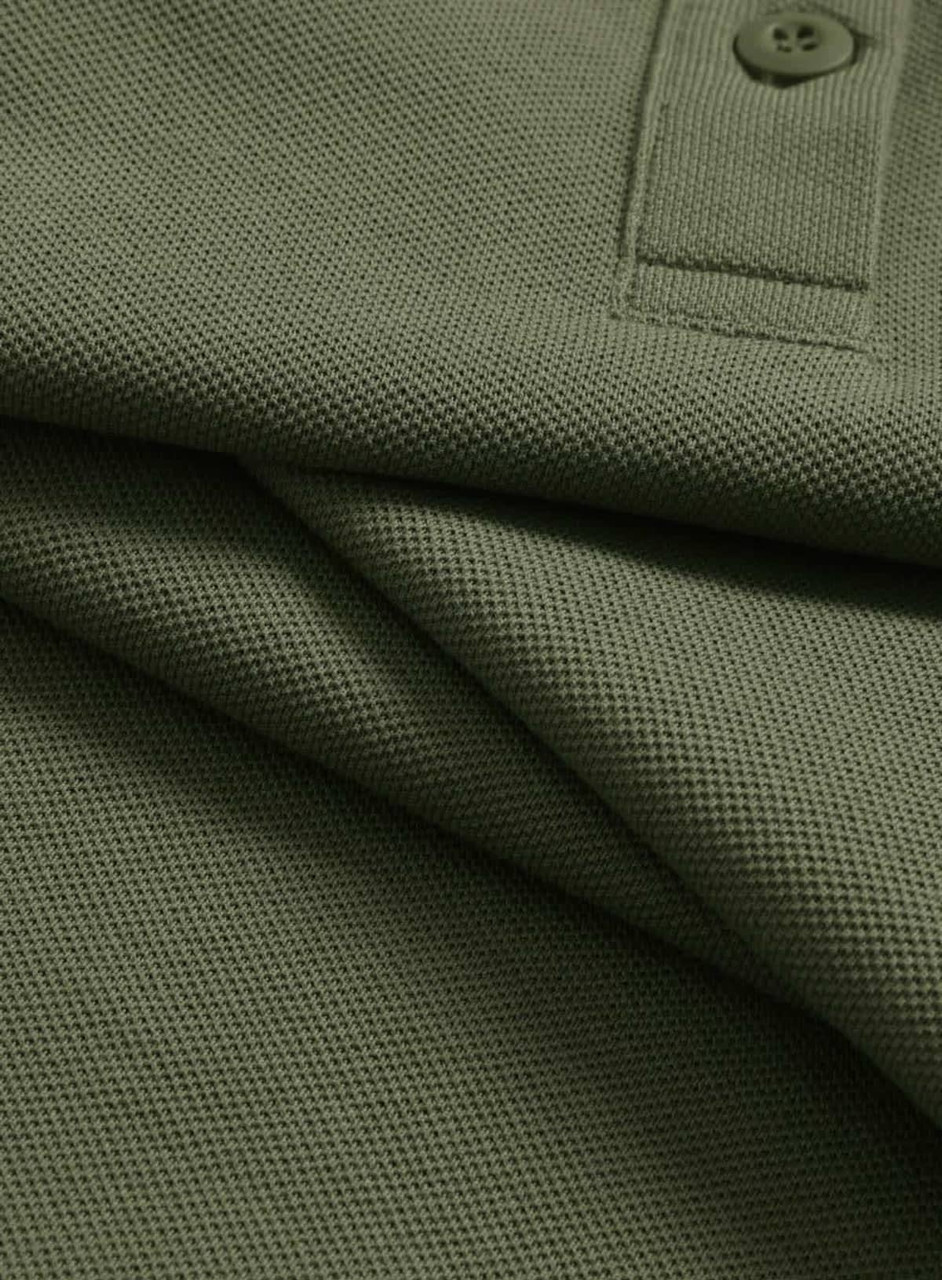 A close-up of an olive green ultrafine cotton pique polo shirt featuring a button and textured fabric.