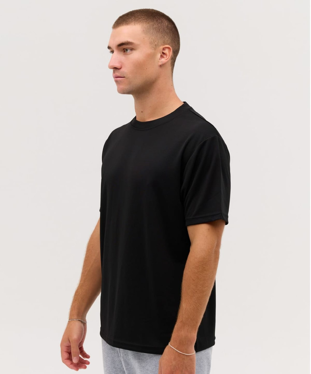 A black Core Tee, featuring a classic crew neck and short sleeves, displayed on a model from the side.