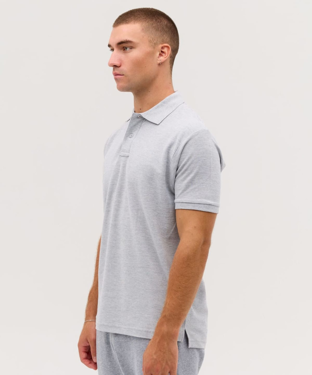 A grey polo shirt displayed on a model in profile, featuring a collar and short sleeves.
