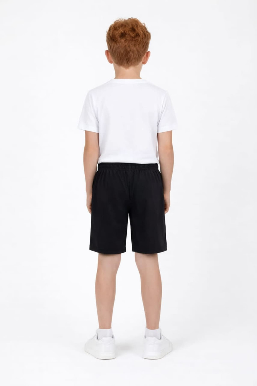 Youth Core Shorts in black, featuring an elastic waistband, shown on a child from the back, wearing a white t-shirt and shoes.