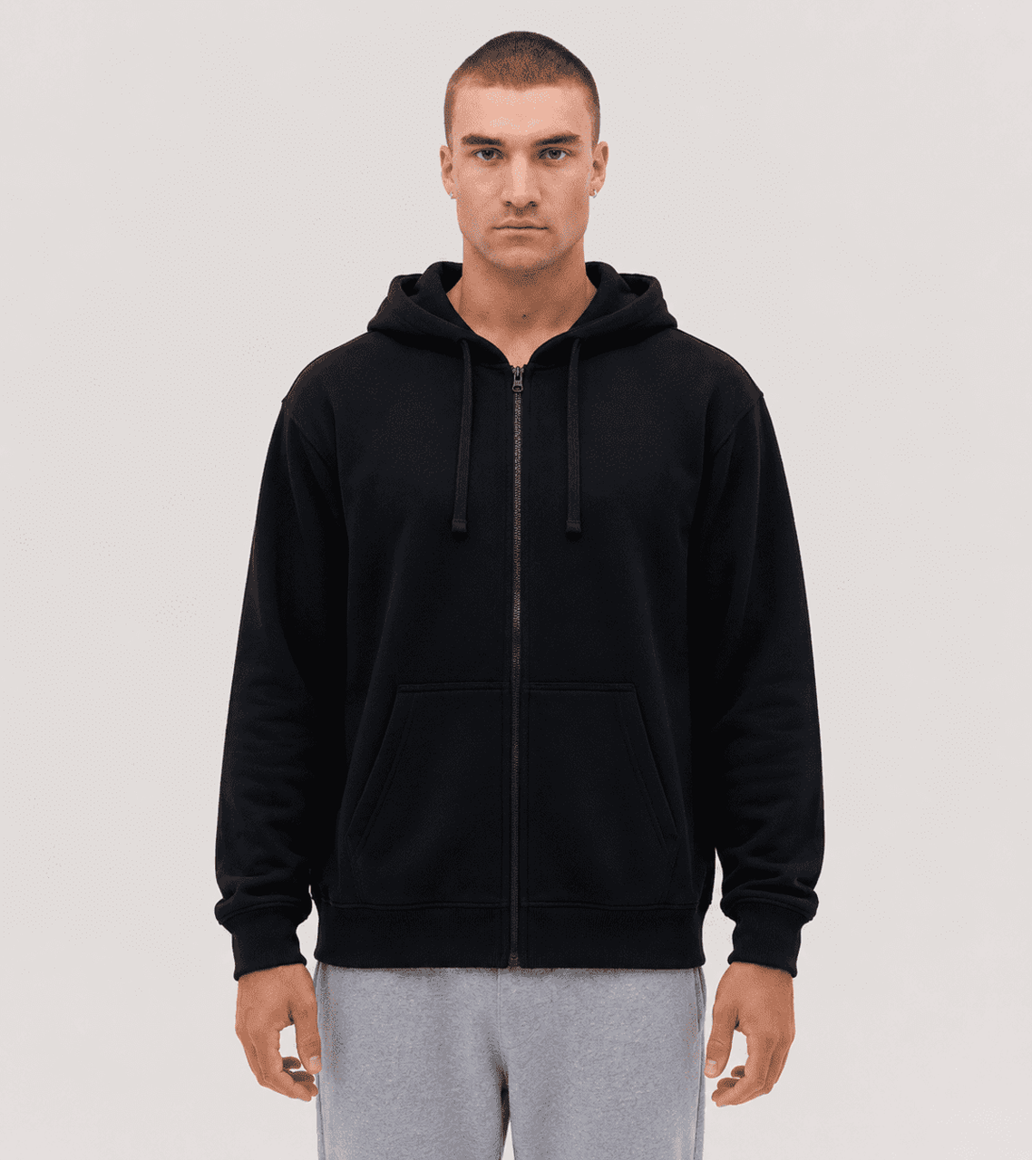 A black zip-up hoodie with a relaxed fit, featuring a hood and drawstrings. The model stands in a neutral pose.