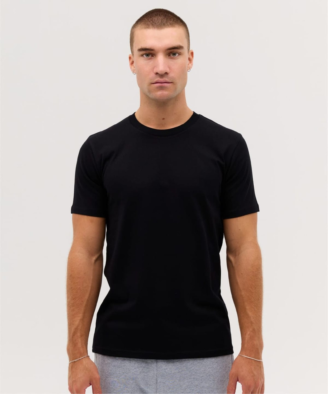 A black classic tee is displayed on a model, showcasing a fitted design and short sleeves.