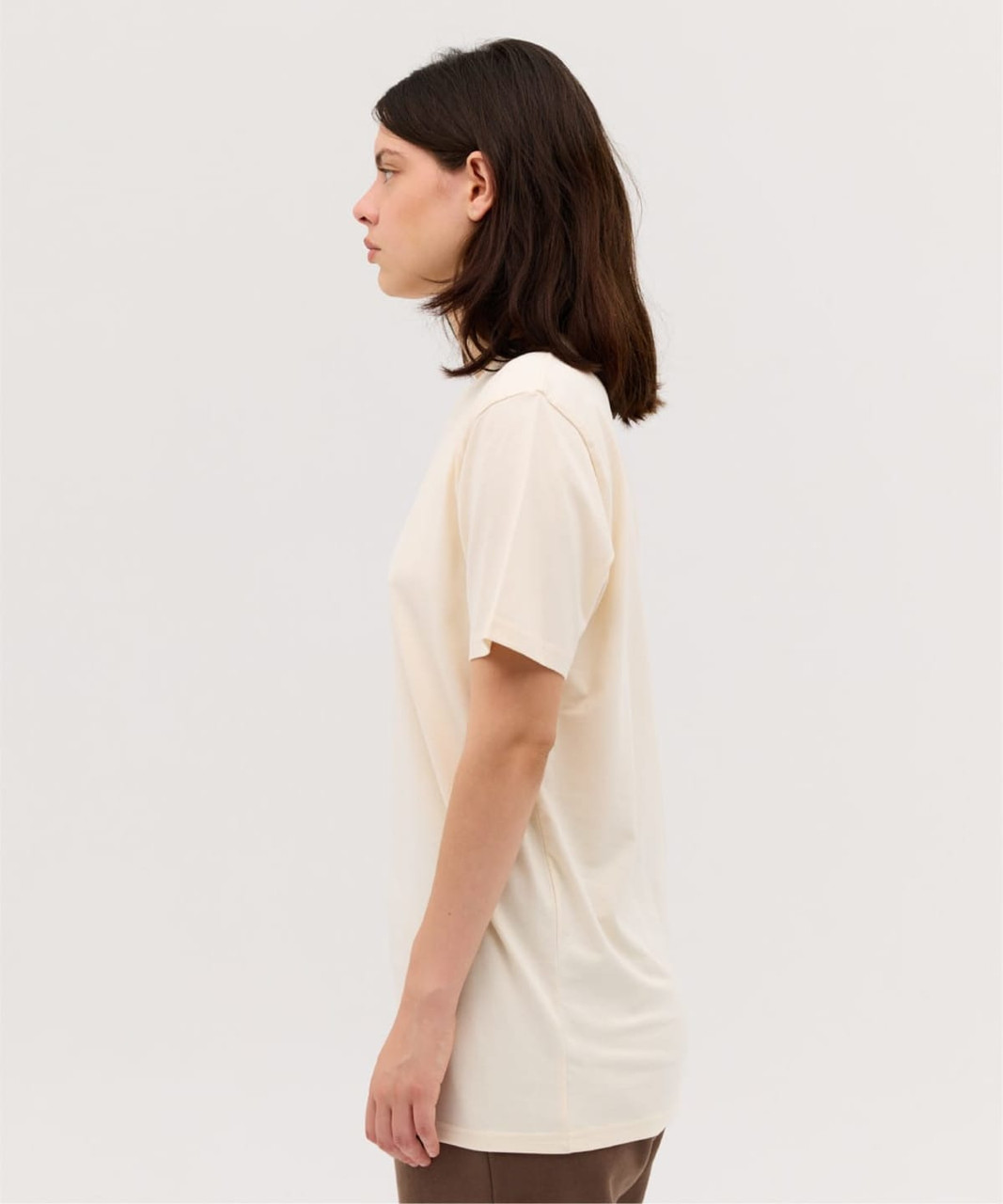 A side view of a classic cream-coloured T-shirt featuring short sleeves and a relaxed fit. The shirt has a logo.