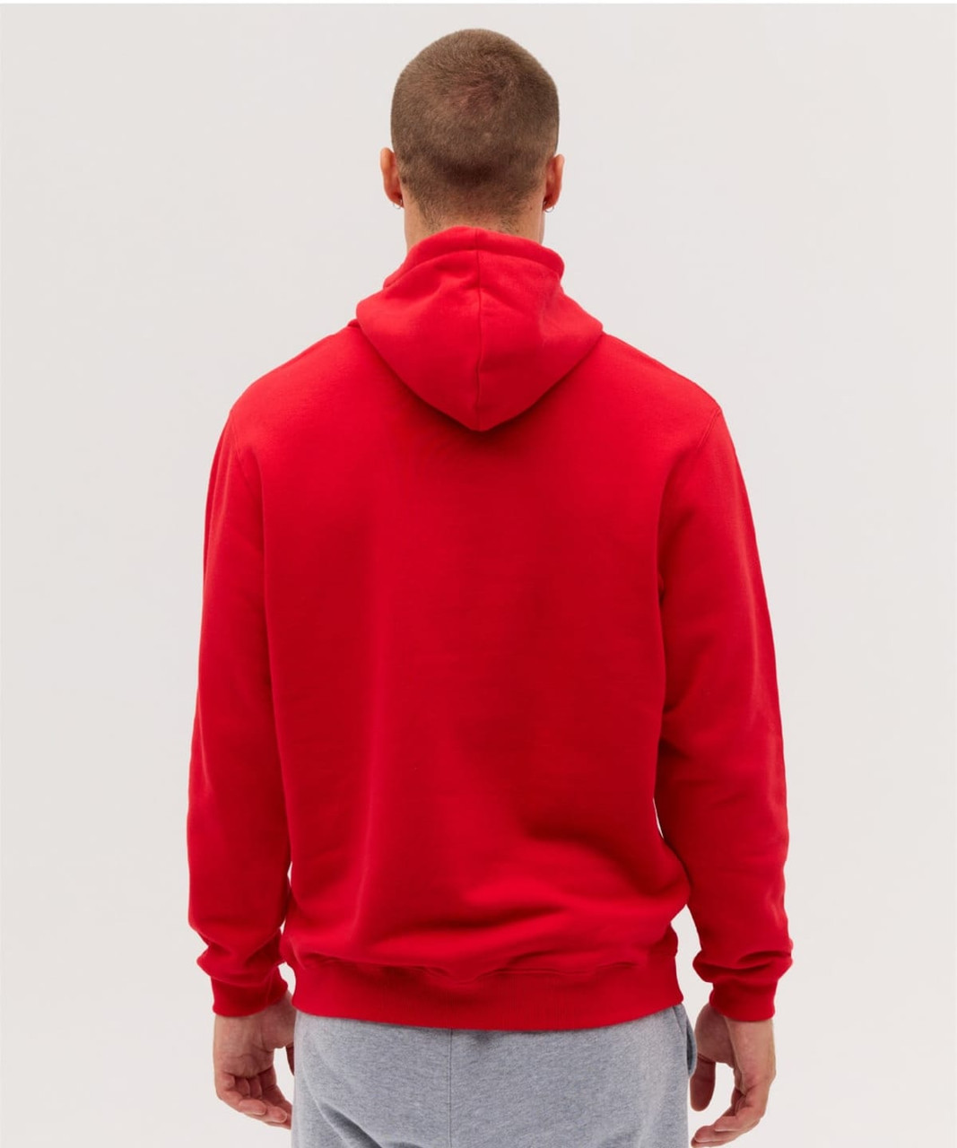 A red hoodie viewed from the back, featuring a hood and a relaxed fit. There is a logo on the garment.