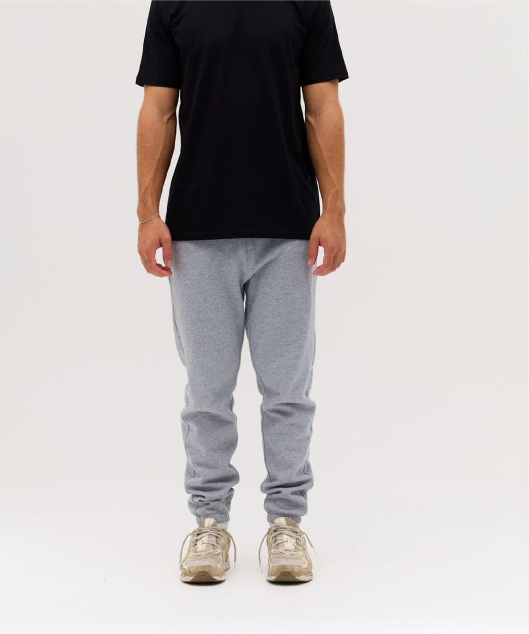 Light grey track pants with a fitted design, paired with a black t-shirt, featuring a logo on the shirt.