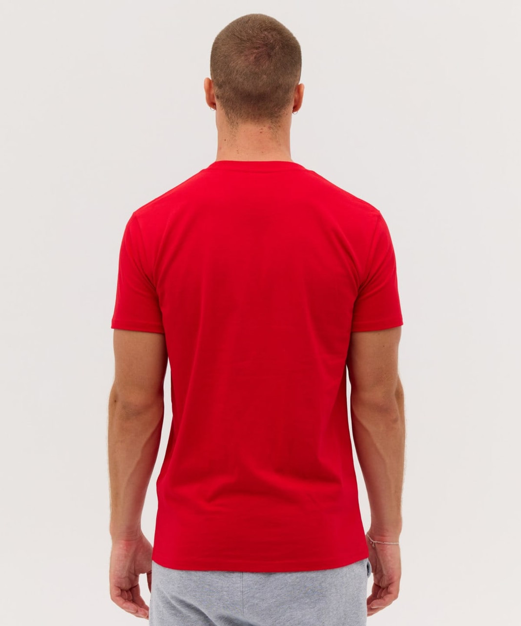 A red t-shirt viewed from the back, featuring a fitted style and short sleeves. It has a small logo on the side.