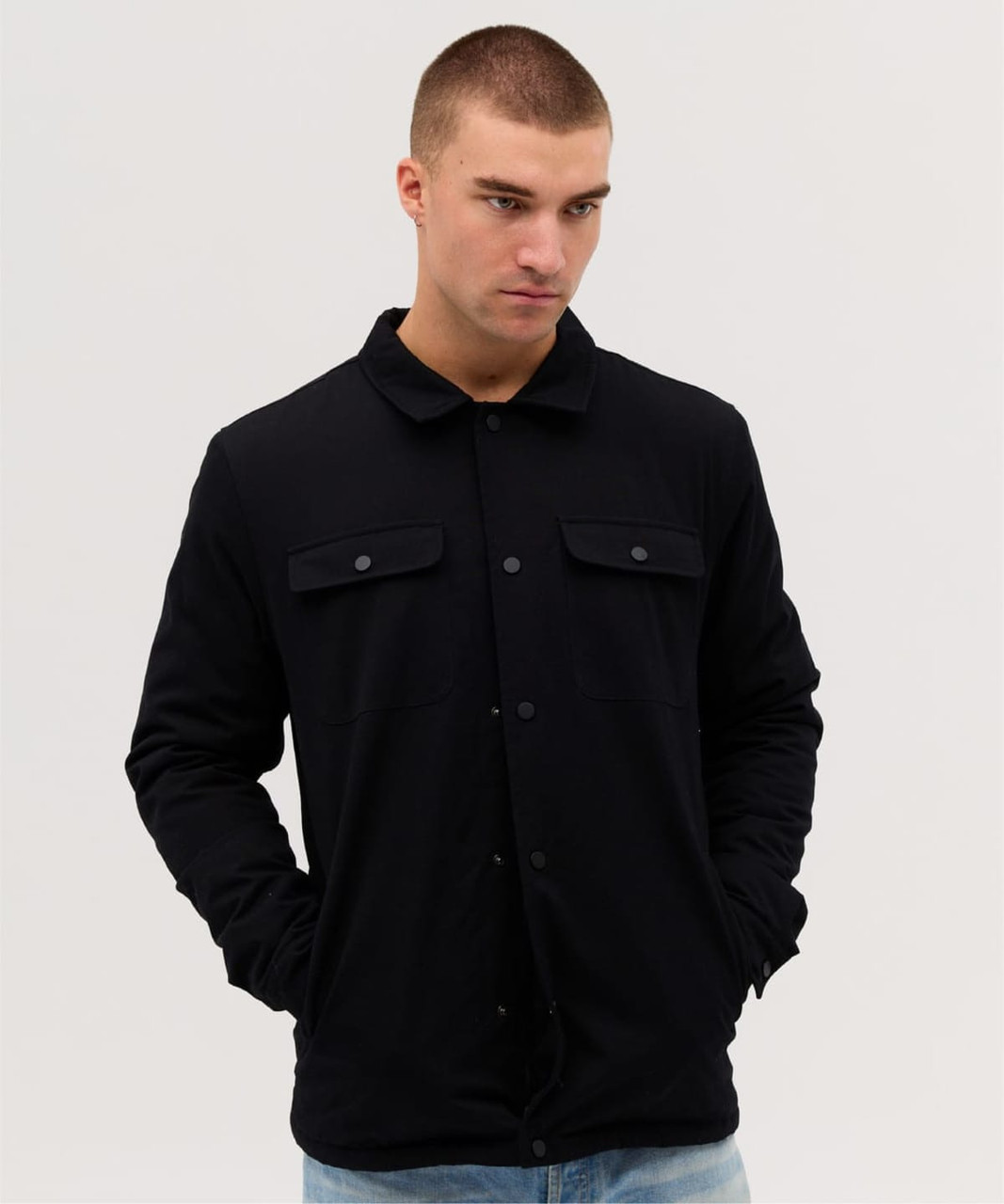 A soft shell jacket in black, featuring a collar and two front pockets, worn by a model.