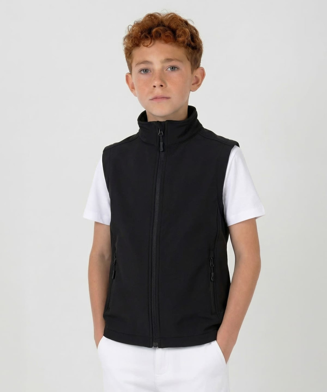 A black youth softshell vest with a high collar and zippered pockets, worn over a white t-shirt.