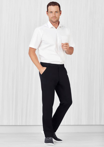 A man models black flat front slacks paired with a white shirt, showcasing a sleek, casual style.