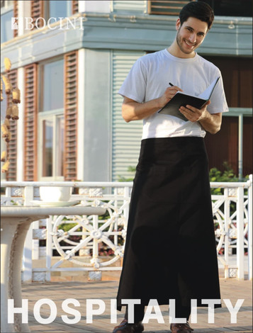 A man in a white T-shirt and black polyester drill apron stands, holding a notepad. The apron has no pockets.