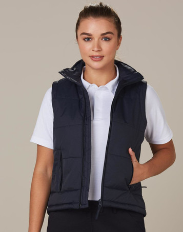 A padded vest in navy blue, featuring a high collar and pockets, worn over a white polo shirt.